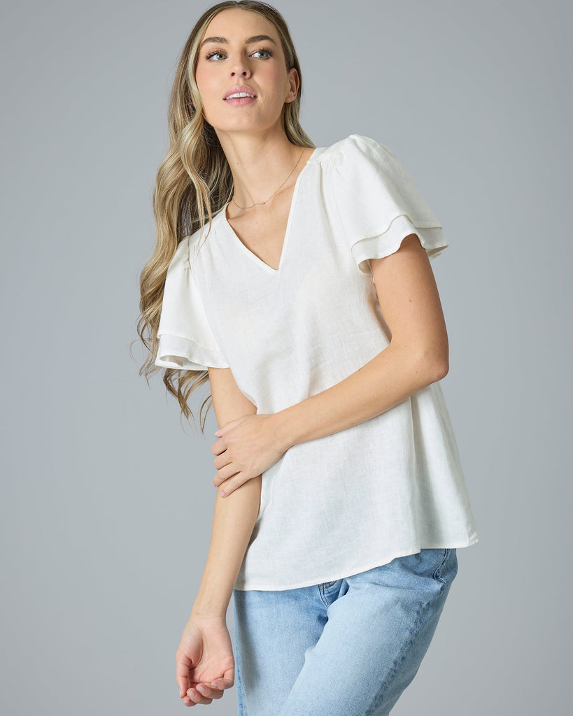 Woman in cream colored short sleeve, v-neck linen blouse