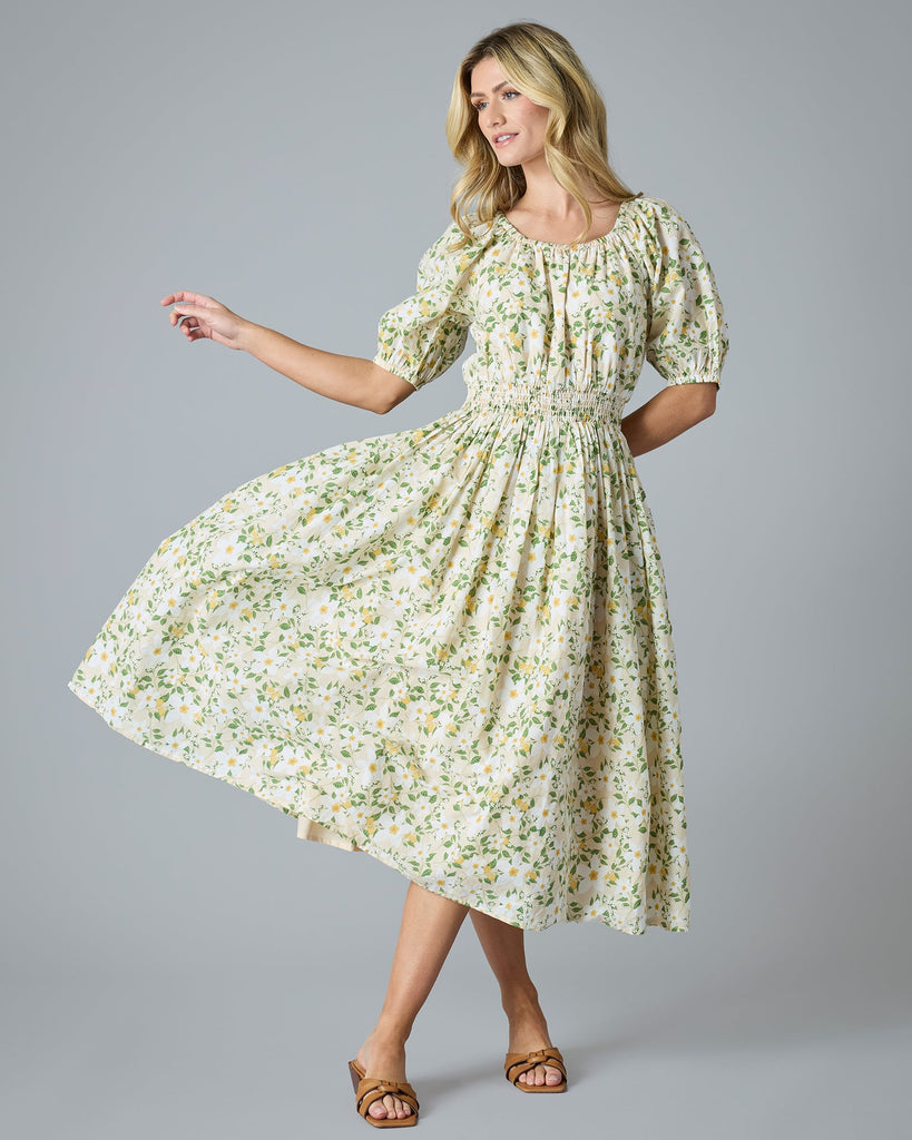 Woman in a green and yellow floral print dress that is midi-length with short sleeves