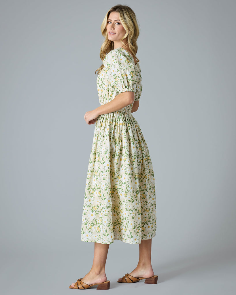 Woman in a green and yellow floral print dress that is midi-length with short sleeves