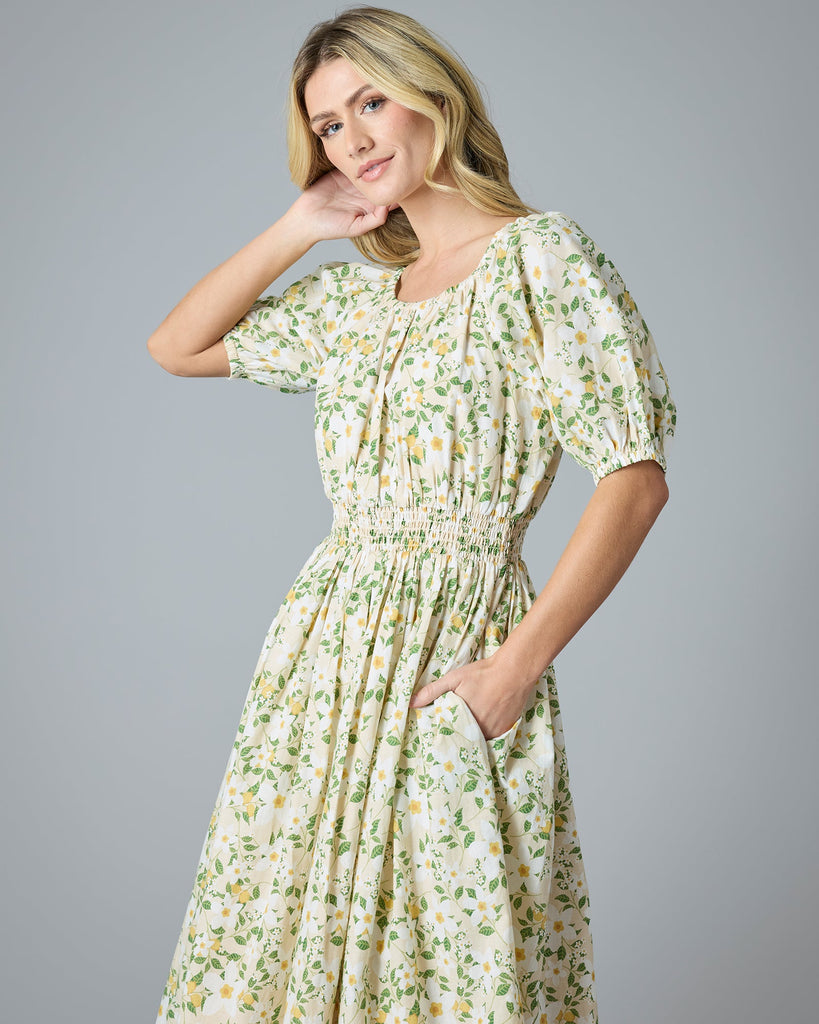 Woman in a green and yellow floral print dress that is midi-length with short sleeves