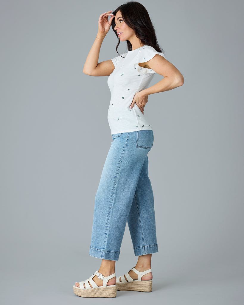 Woman in a white, short sleeved, embroidered t-shirt