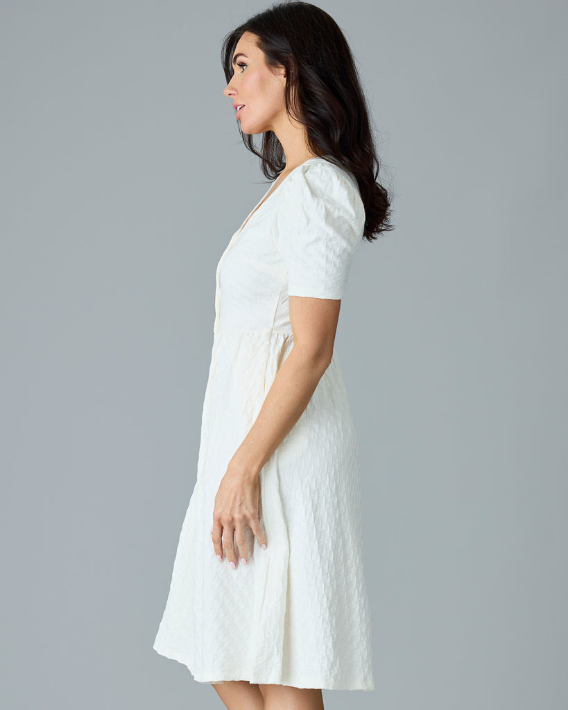 Woman in a white, short sleeve, v-neck dress