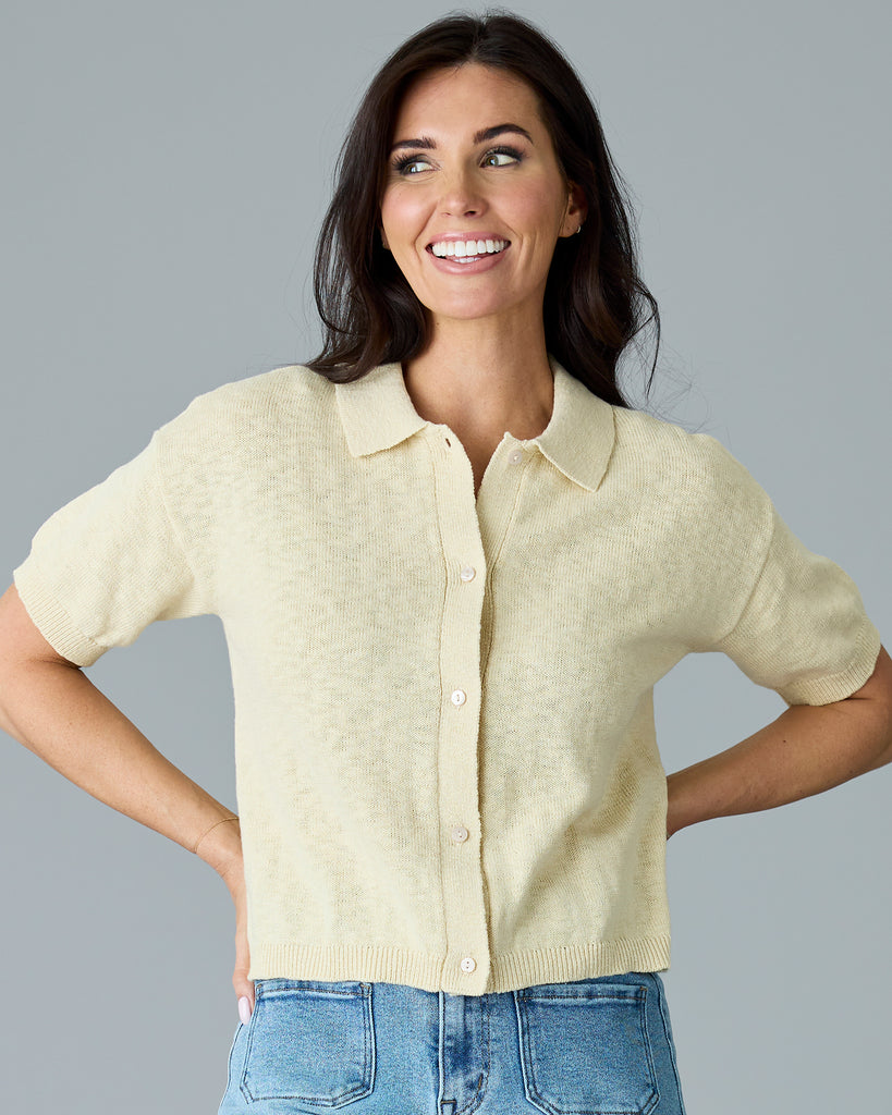 Woman in a tan, short sleeved, collared cardigan