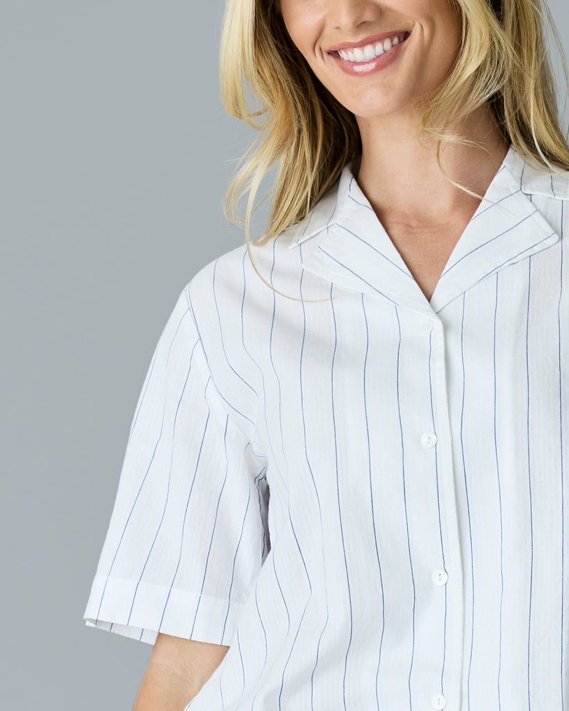 Woman in a white with blue vertical stripes, short sleeve buttondown