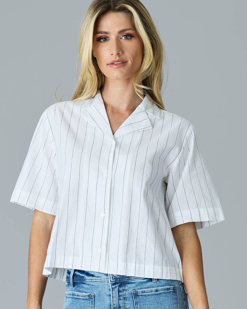 Woman in a white with blue vertical stripes, short sleeve buttondown