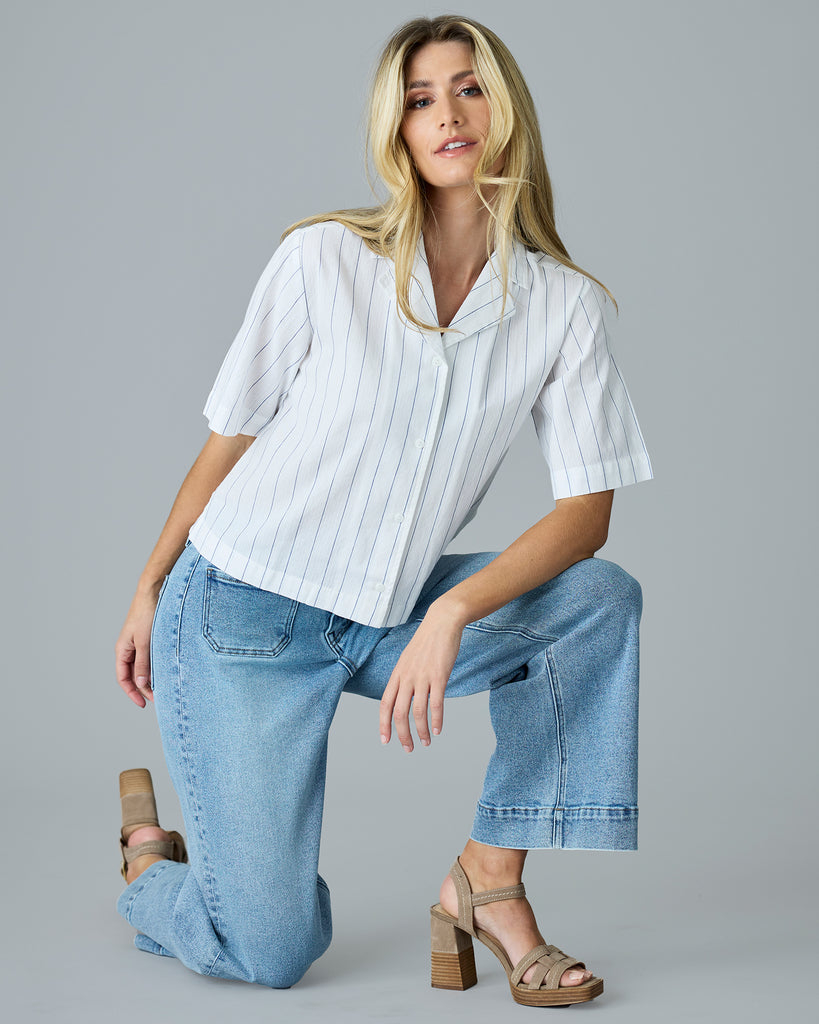 Woman in a white with blue vertical stripes, short sleeve buttondown