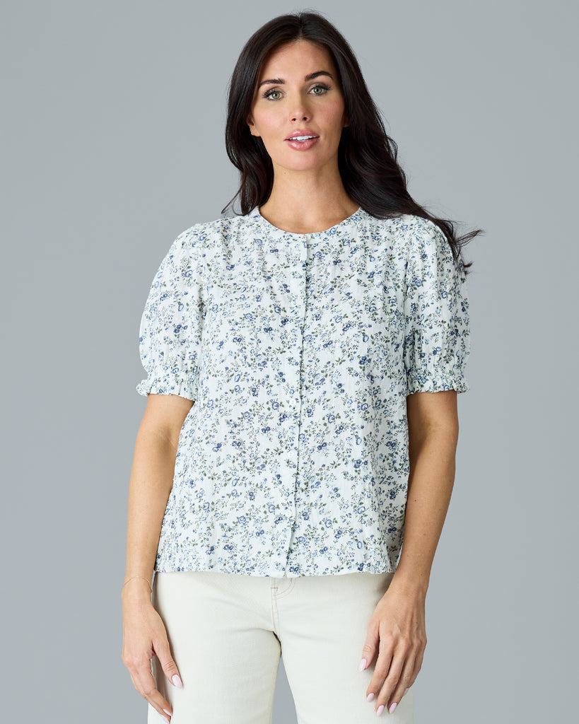 Woman in a white with blue and green floral print short sleeve blouse