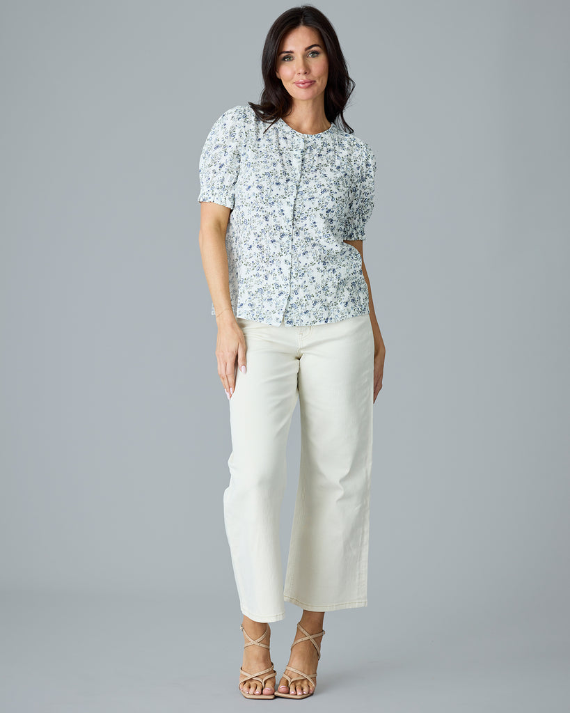 Woman in a white with blue and green floral print short sleeve blouse