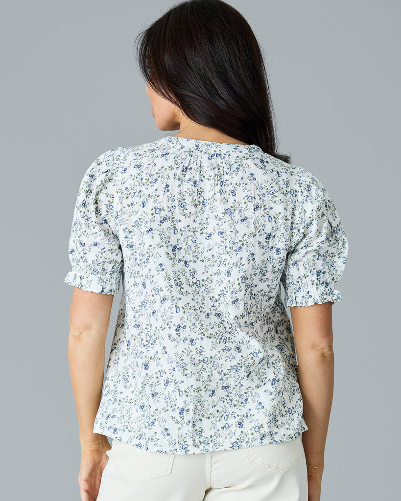 Woman in a white with blue and green floral print short sleeve blouse