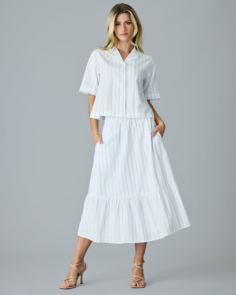 Woman in a white with blue vertical stripes, short sleeve buttondown with matching skirt