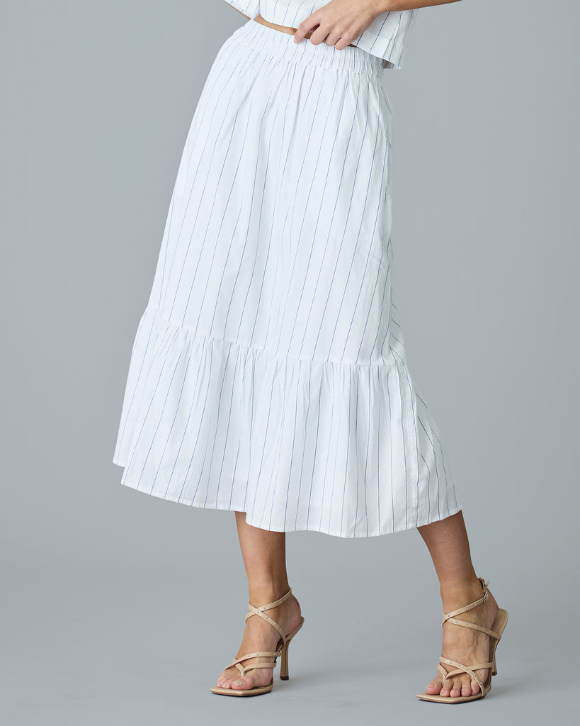 Woman in a white with blue vertical stripes midi length skirt