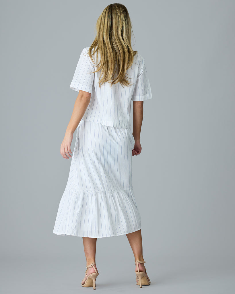 Woman in a white with blue vertical stripes midi length skirt