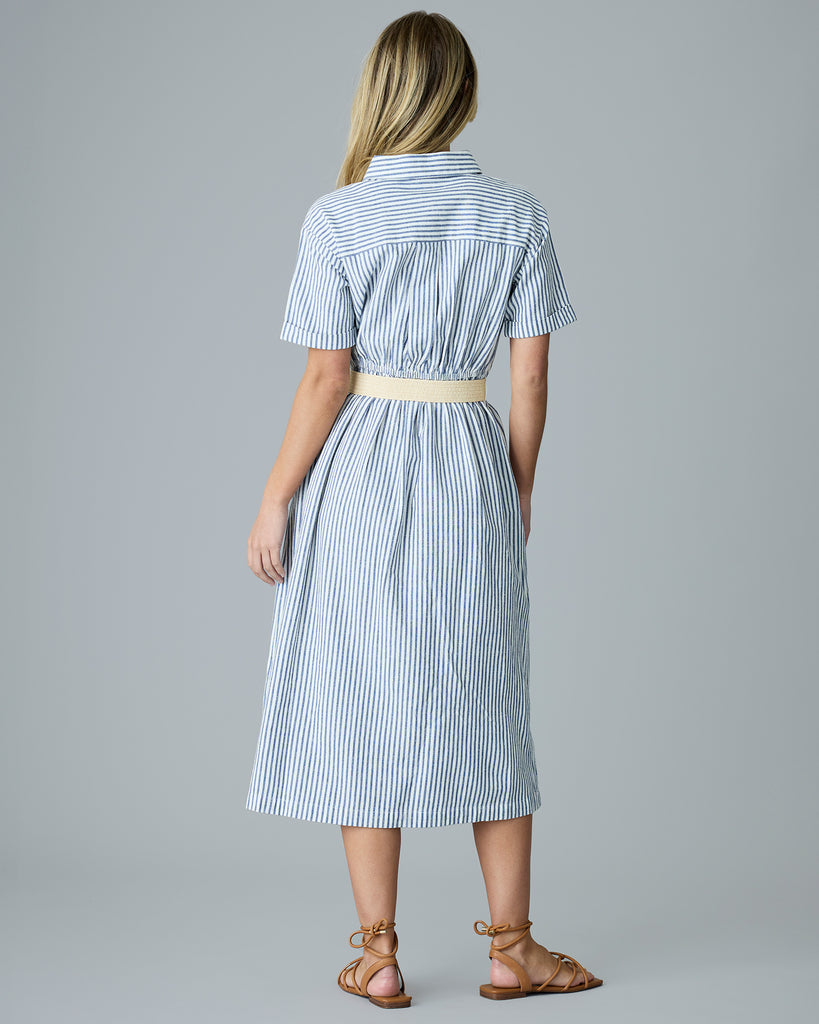 Woman in a blue and white vertical stripe, short sleeve linen dress