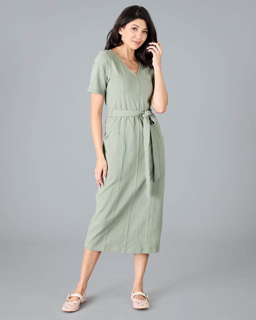 Woman in a green short sleeve dress with tie around waist