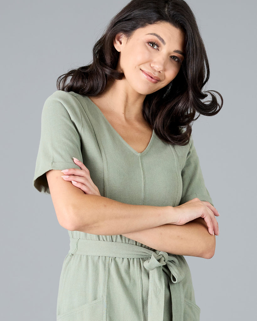 Woman in a green short sleeve dress with tie around waist