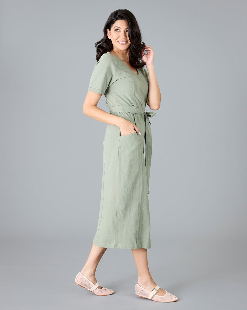 Woman in a green short sleeve dress with tie around waist