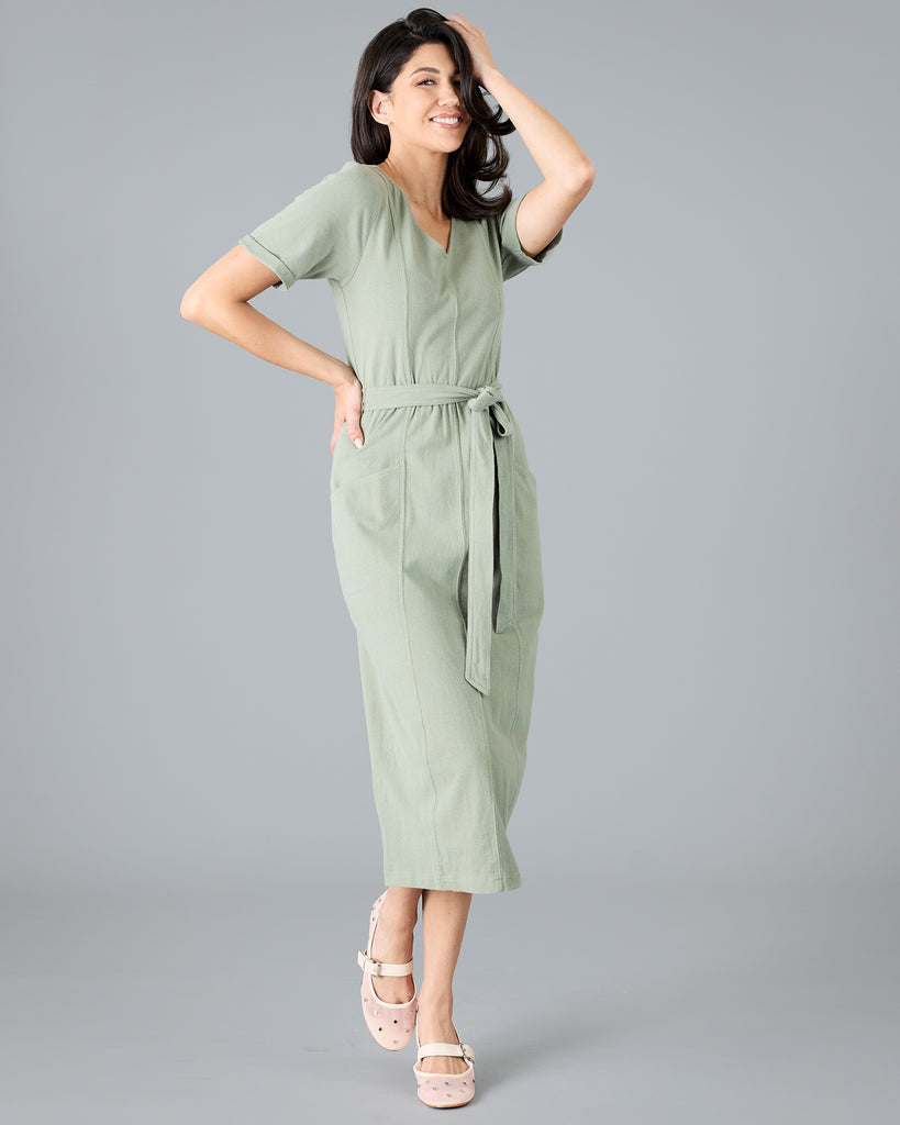 Woman in a green short sleeve dress with tie around waist