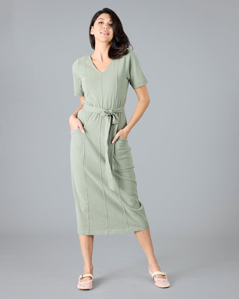 Woman in a green short sleeve dress with tie around waist