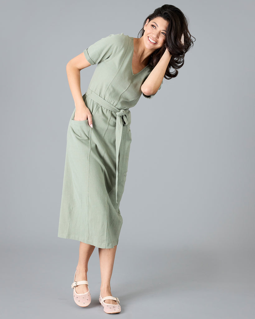 Woman in a green short sleeve dress with tie around waist