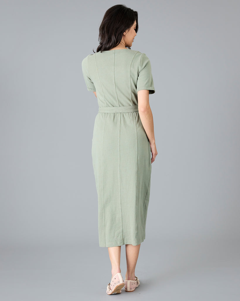 Woman in a green short sleeve dress with tie around waist