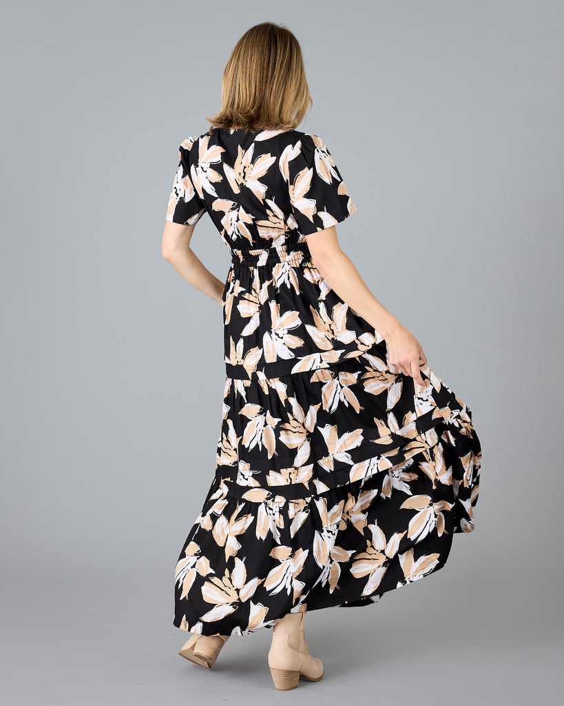 Woman in a black with white/tan floral print, short sleeve maxi dress