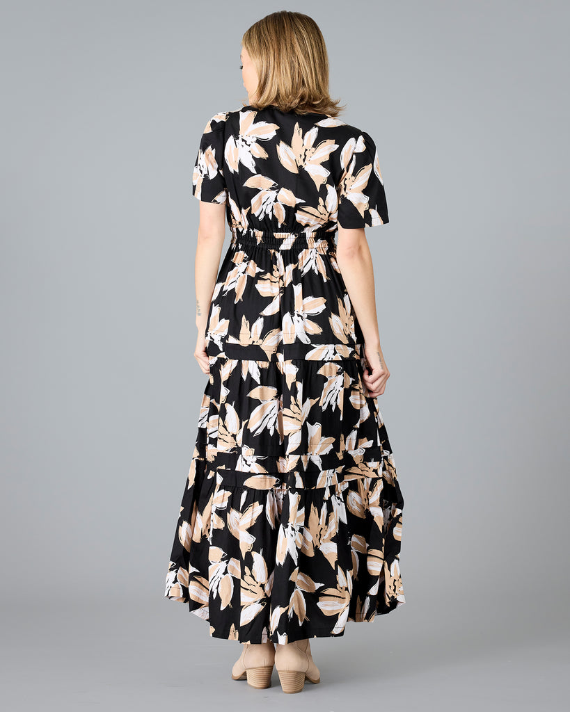 Woman in a black with white/tan floral print, short sleeve maxi dress