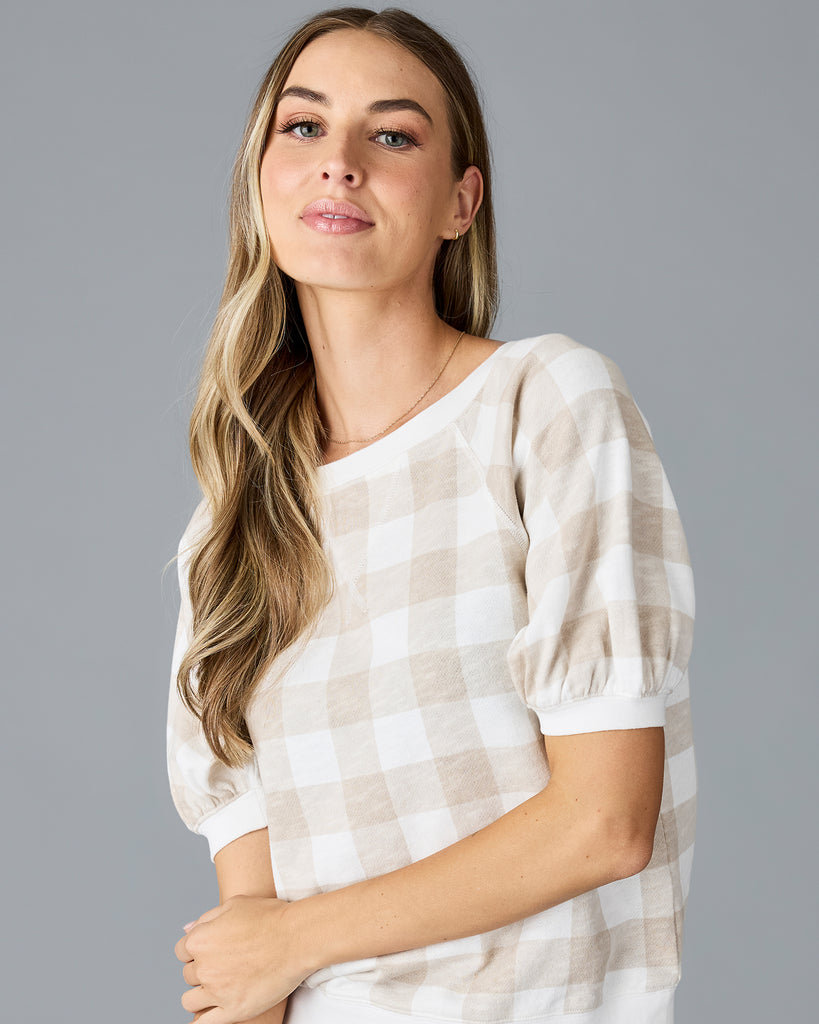 Woman in a tan and white plaid, short sleeve thing sweater