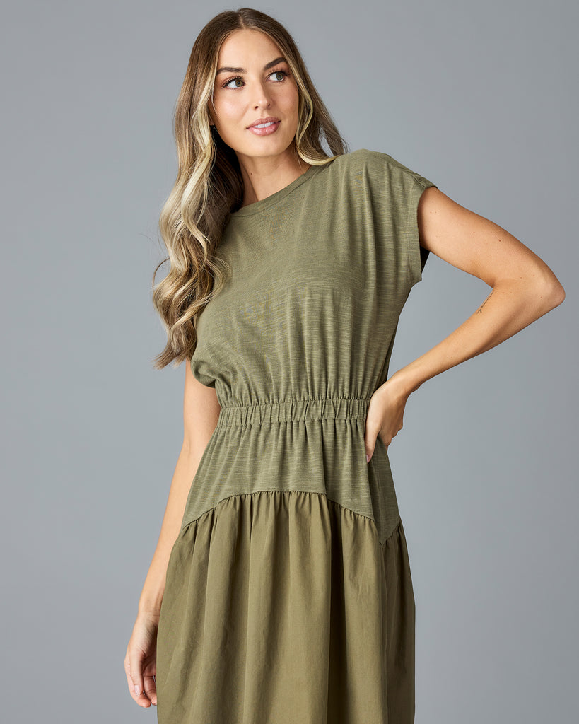 Woman in an olive green, short sleeve midi dress