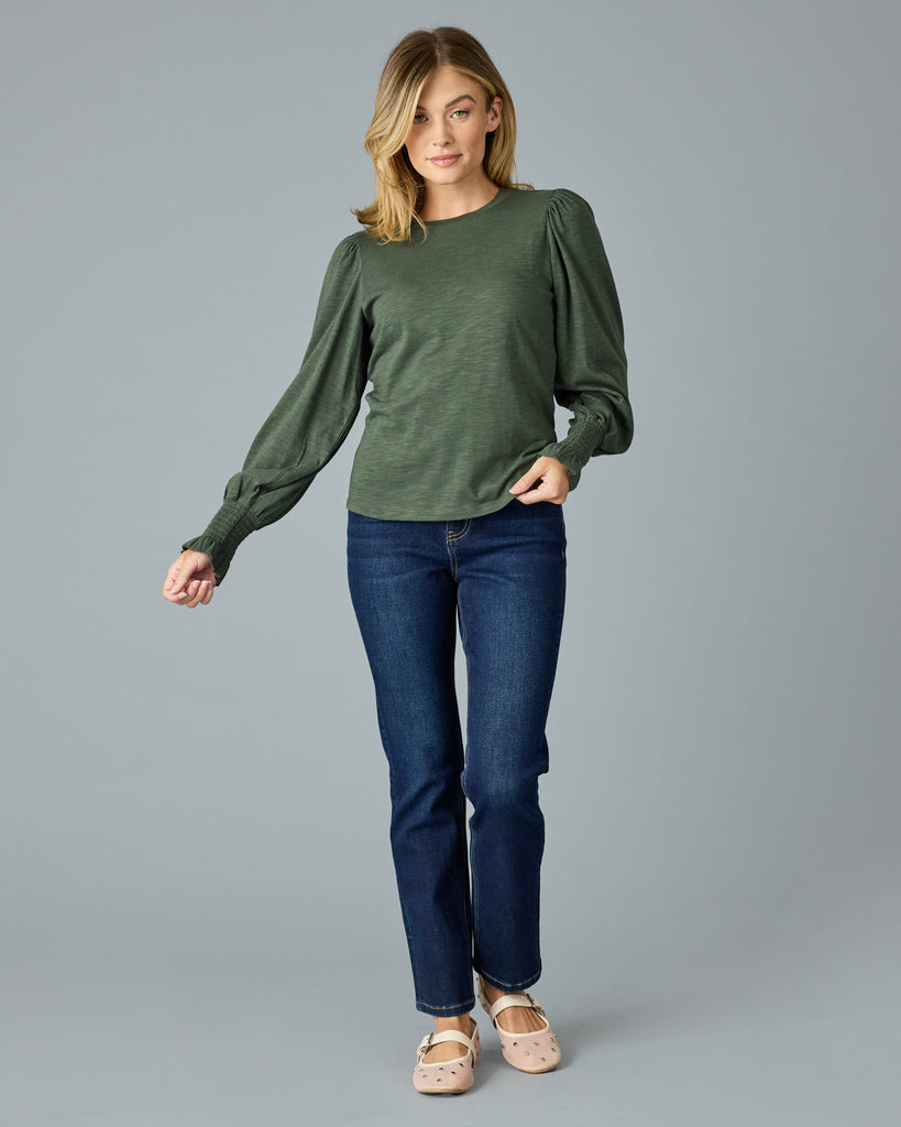 Woman in a green, long sleeve tshirt with ruffle details on sleeve