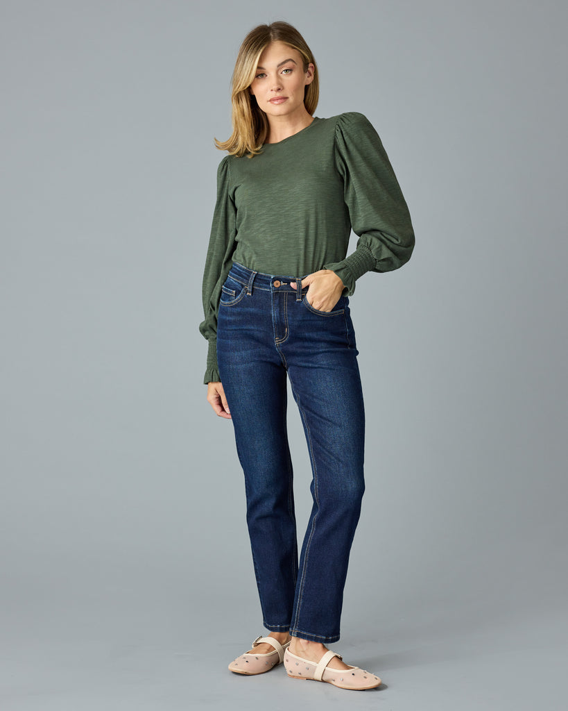 Woman in a green, long sleeve tshirt with ruffle details on sleeve