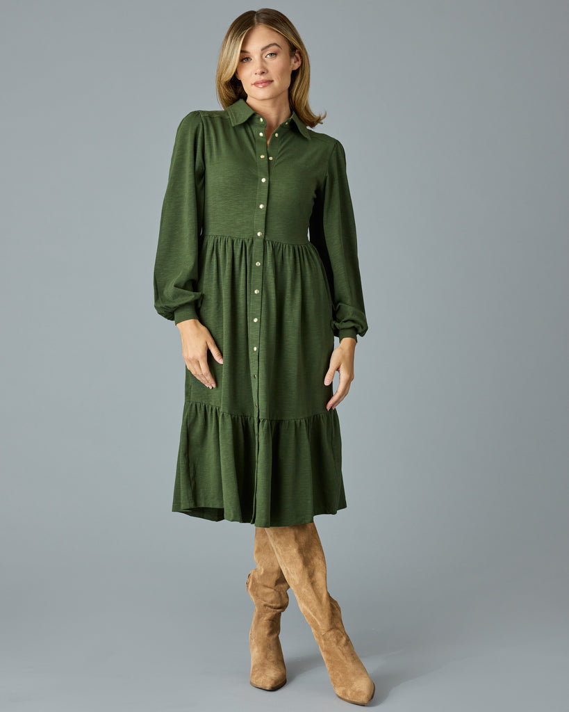 Woman in a green, long sleeve, collared, buttondown dress that is midi length