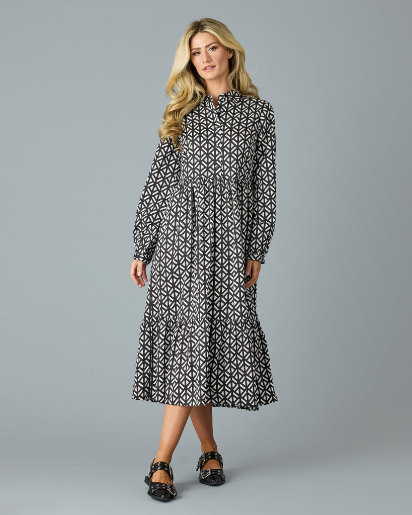 Woman in a black and white geometric print long sleeve midi dress