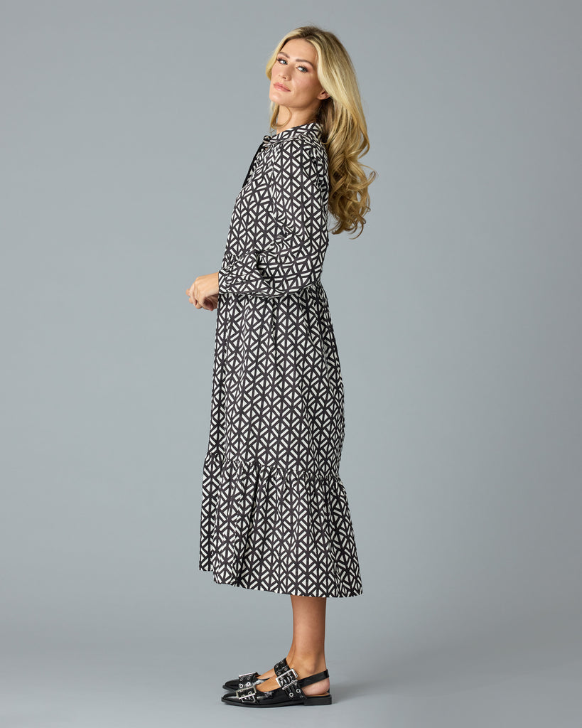 Woman in a black and white geometric print long sleeve midi dress