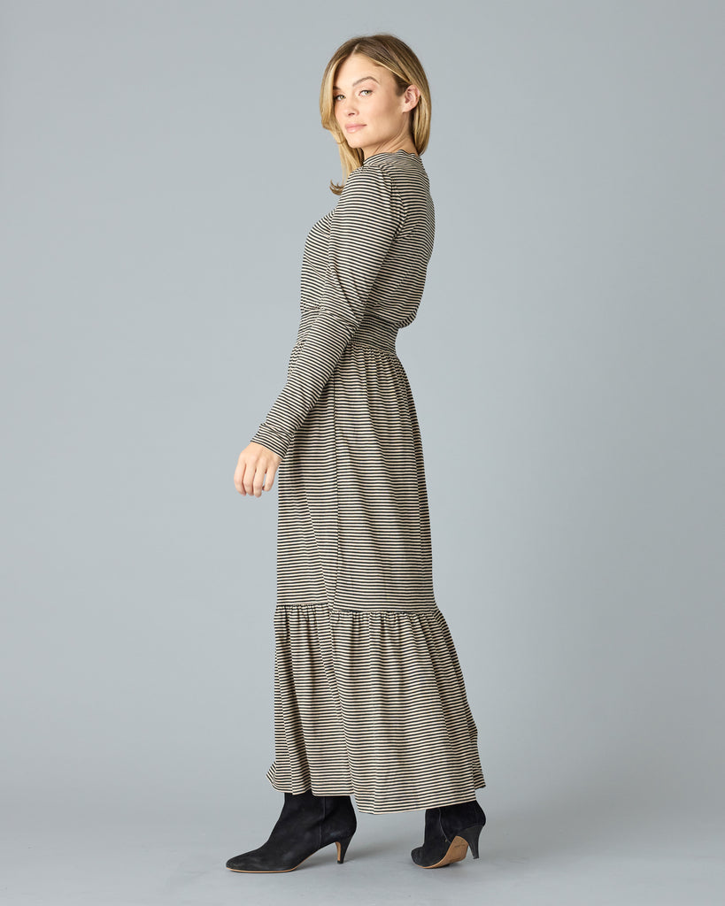 Woman in a black and tan thin striped maxi dress with long sleeves, a mock neck and pockets