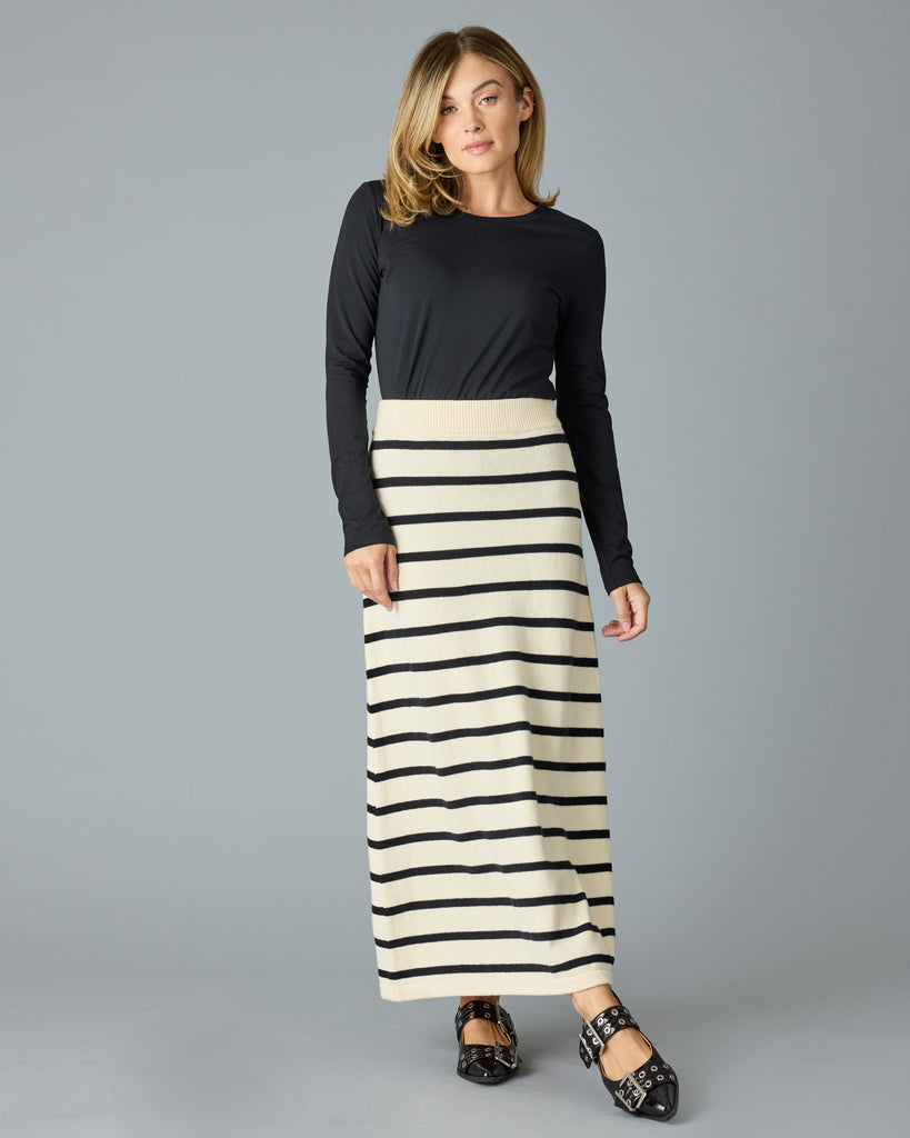 Woman in a black and tan striped maxi sweater skirt with a black top