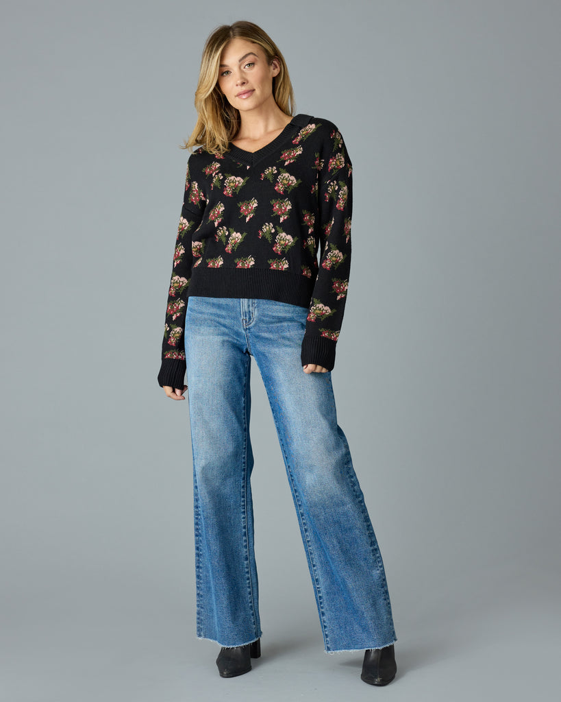 Woman in a black with floral print, long sleeve, v-neck sweater