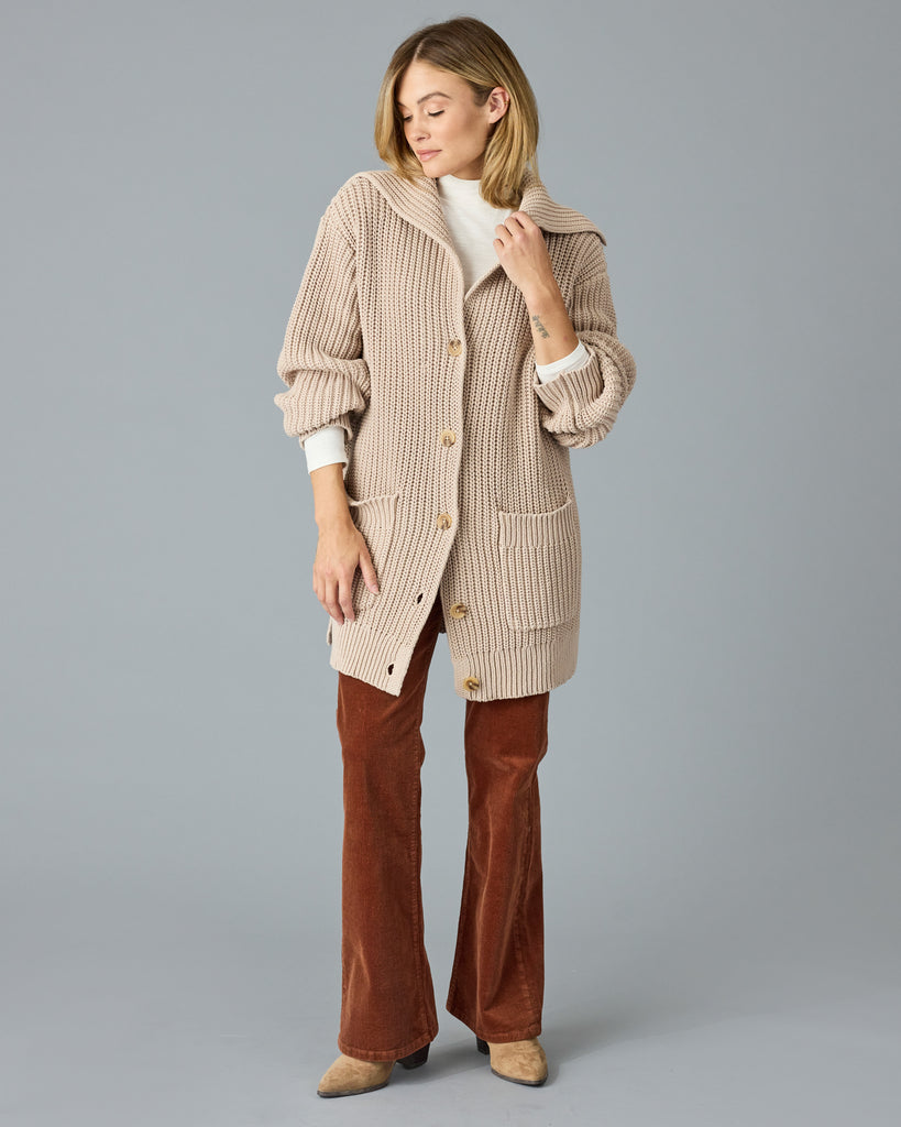 Woman in a tan, oversized cardigan