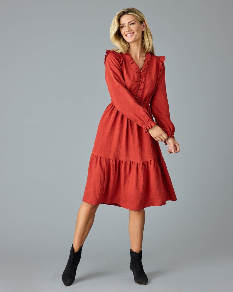 Woman in a red, long sleeve, v-neck, midi dress with ruffles down the front