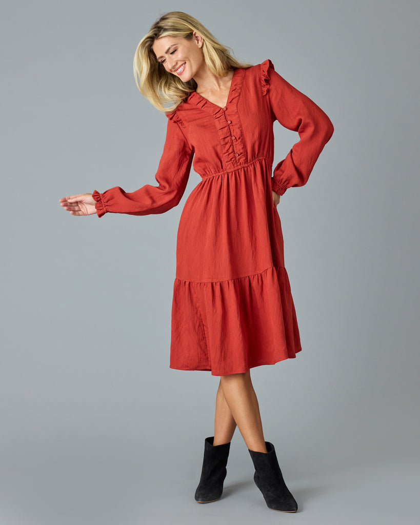 Woman in a red, long sleeve, v-neck, midi dress with ruffles down the front