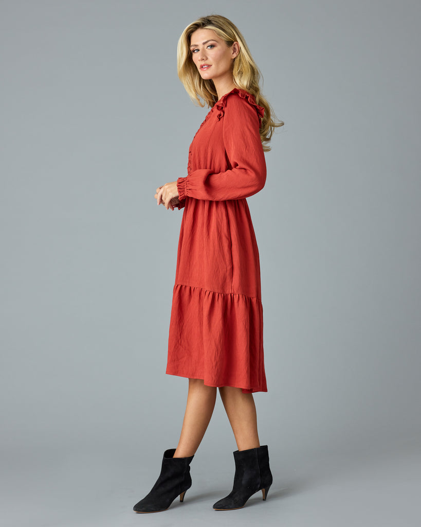 Woman in a red, long sleeve, v-neck, midi dress with ruffles down the front