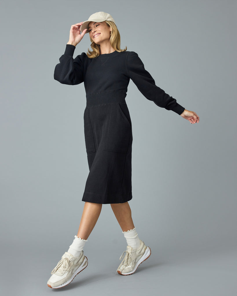 Woman in a black, long sleeve, midi length sweater dress