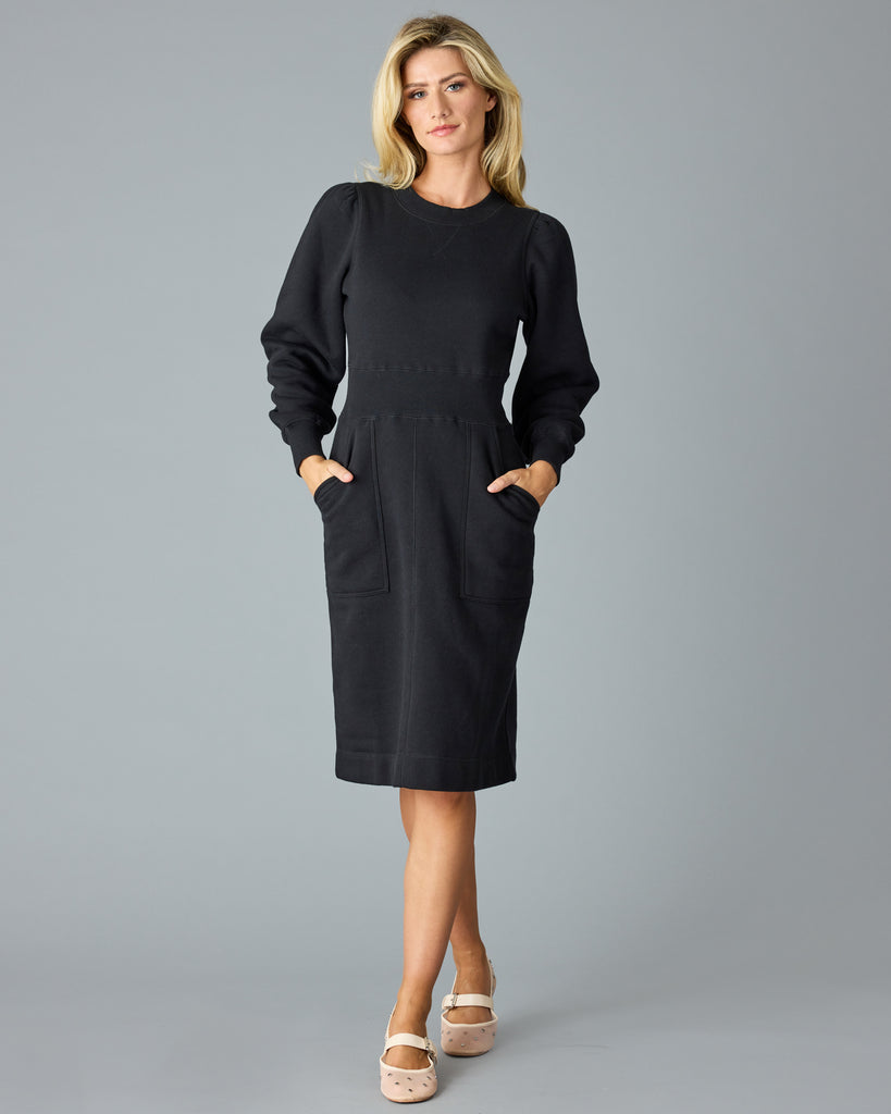 Woman in a black, long sleeve, midi length sweater dress