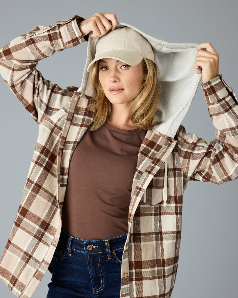 Woman in a tan plaid buttondown with a sweater hood attached