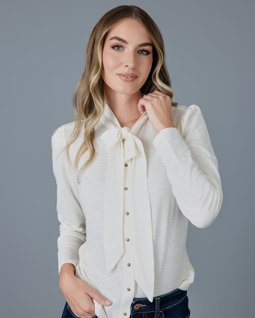 Woman in a white long sleeve knit buttondown with tie at neck