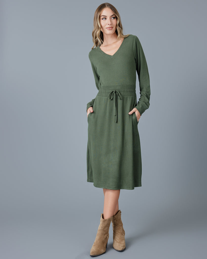 Woman in a green long sleeve, v-neck, midi-length sweater dress