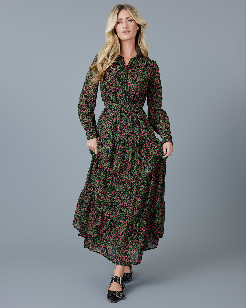 Woman in a green, pink and black printed long sleeve maxi dress