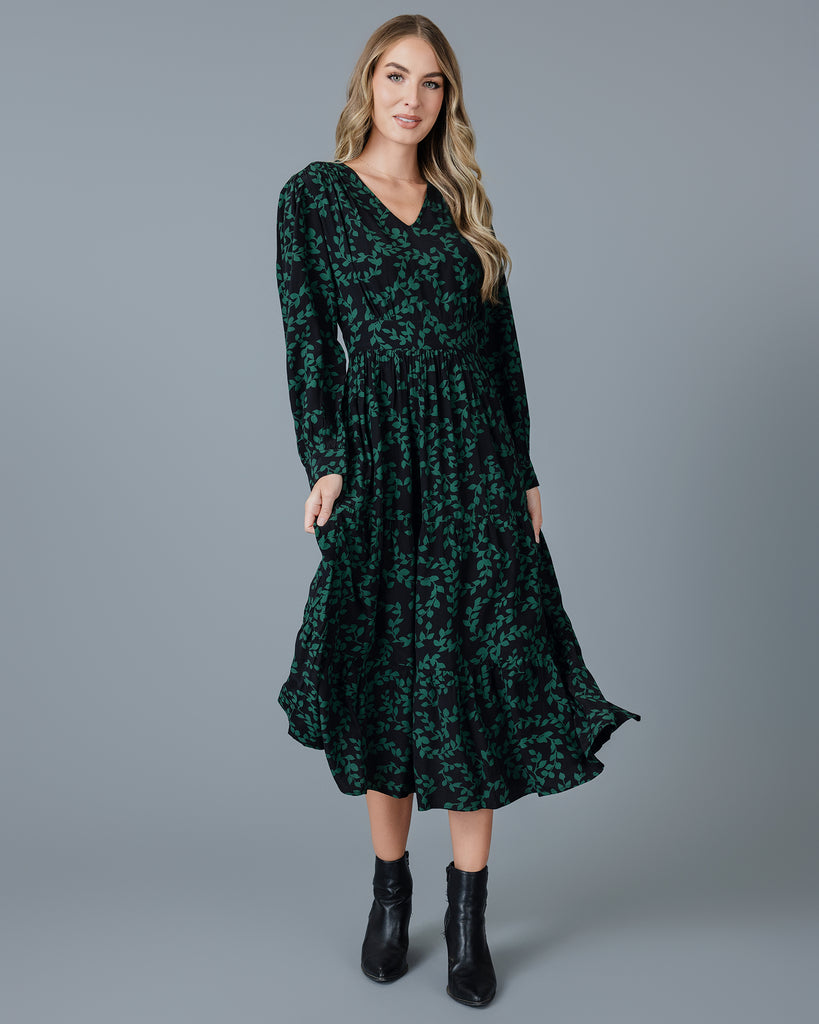 Woman in a green and black long sleeve v-neck midi dress