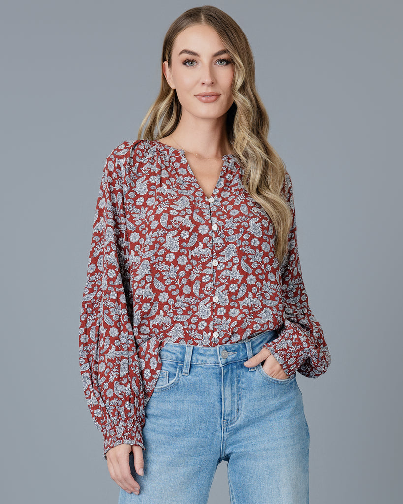 Woman in a red paisley printed long sleeve blouse