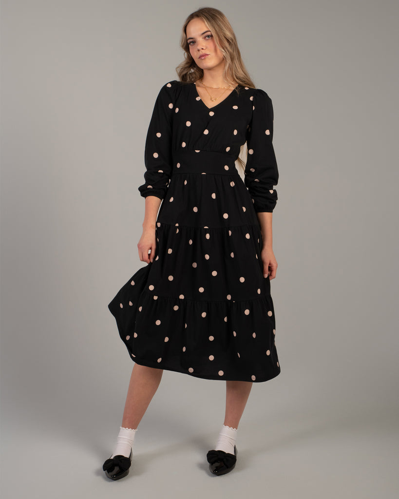 Woman in a black with white polka dot, 3/4 sleeve, v-neck knit dress