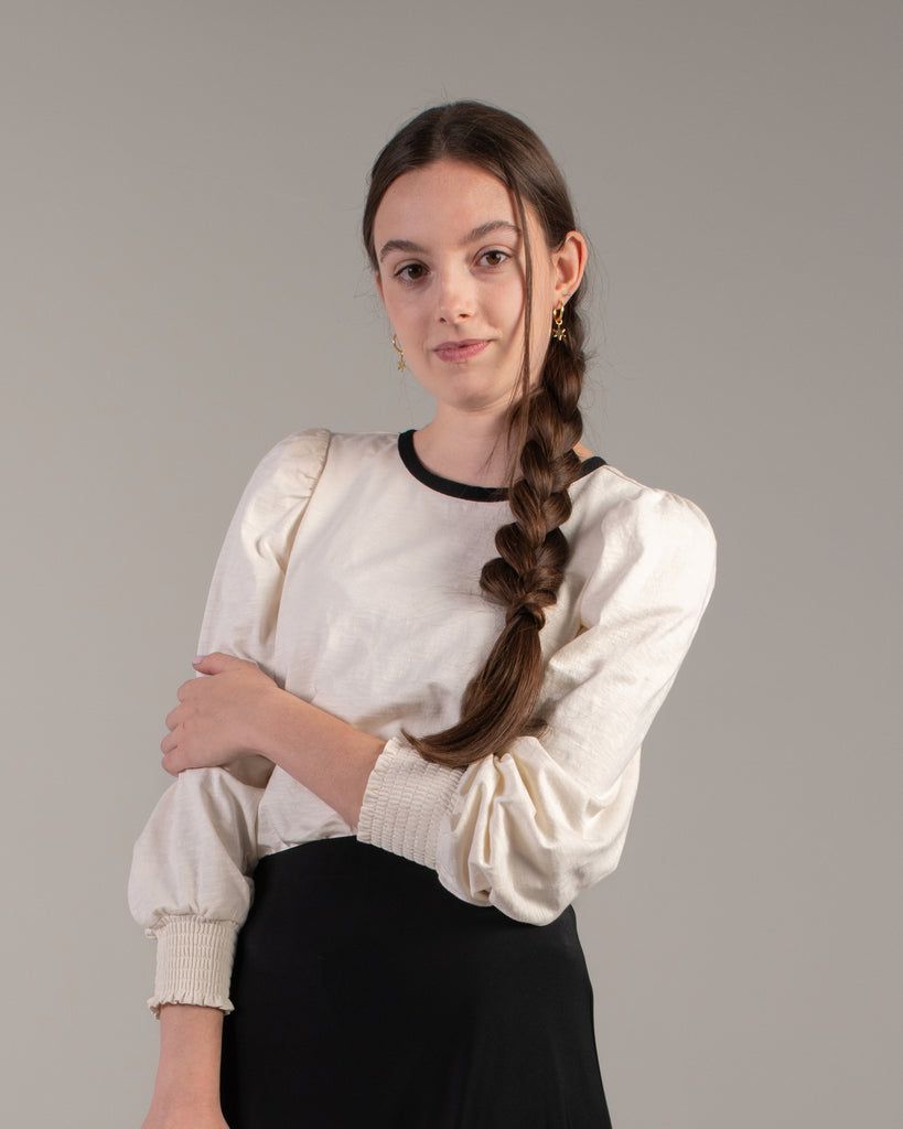 Woman in a white blouse with black detail around neckline